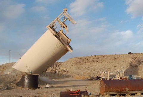 1979 Ford Bronco - Industrial silo appears to be collapsing in a remote, dusty area under a cloudy sky.