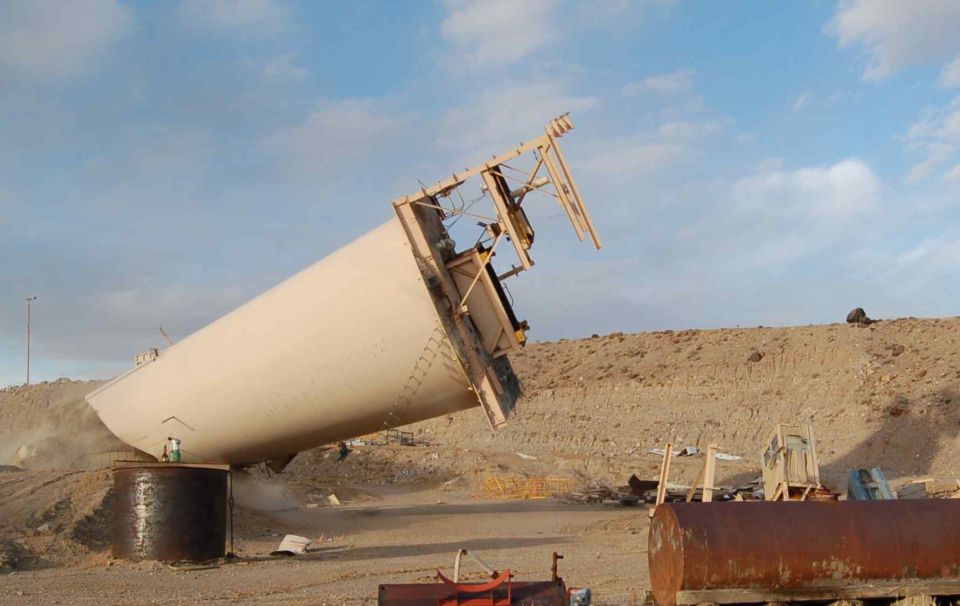 Fallen industrial silo in a desert landscape with construction debris