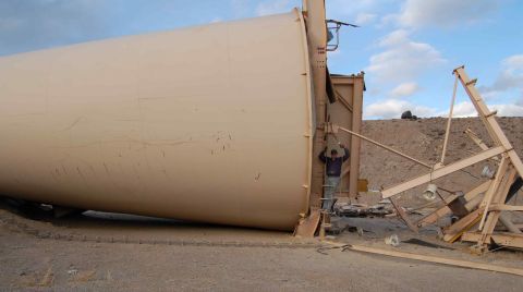 1979 Ford Bronco - A large silo has fallen over, with a person inspecting the damage. Construction materials are strewn about the scene.