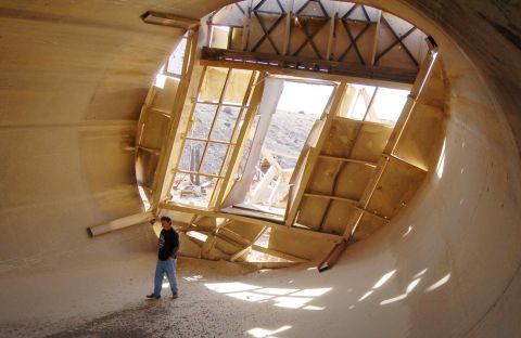1979 Ford Bronco - A man stands inside a cavernous, unfinished concrete structure with exposed wooden framing and large windows.