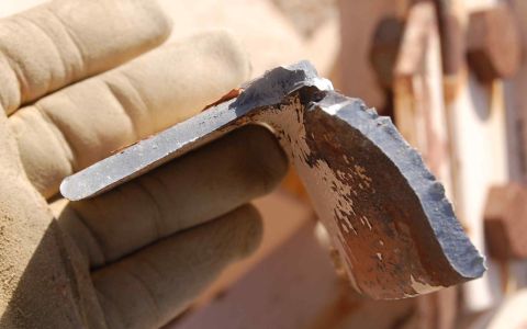 1979 Ford Bronco - A gloved hand holds a piece of broken metal, revealing rust and chipped paint, with a Supermotors.net watermark visible.