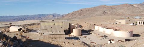 1979 Ford Bronco - Desert industrial site features multiple buildings and large storage tanks under a clear blue sky.