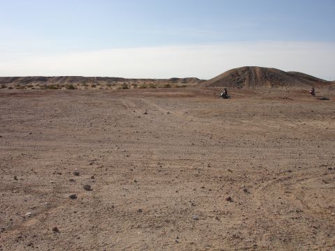1996 Ford Bronco - Two dirt bikes are seen riding in a vast, arid landscape under a clear blue sky.