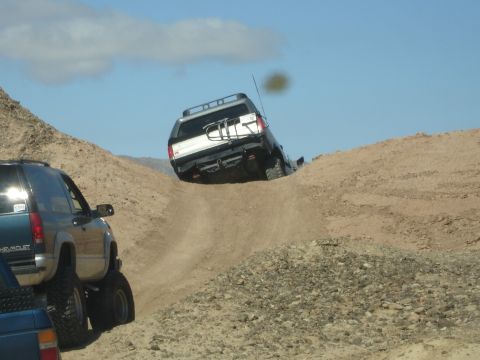 1996 Ford Bronco - Off-road vehicles navigate a challenging dirt hill climb on a sunny day.