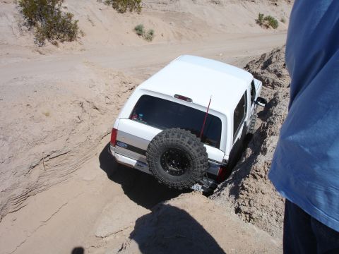 1996 Ford Bronco - White 1996 Ford Bronco navigating a difficult off-road trail, stuck in a sandy ditch.