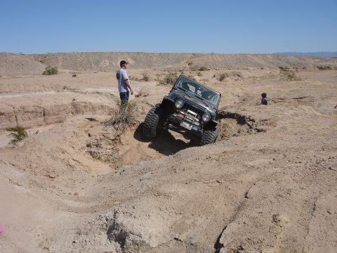 1996 Ford Bronco - Jeep Wrangler TJ tackling a challenging off-road course in a desert environment.