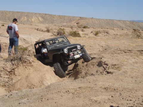 1996 Ford Bronco - A black Jeep Wrangler navigates a challenging off-road obstacle in a desert landscape.
