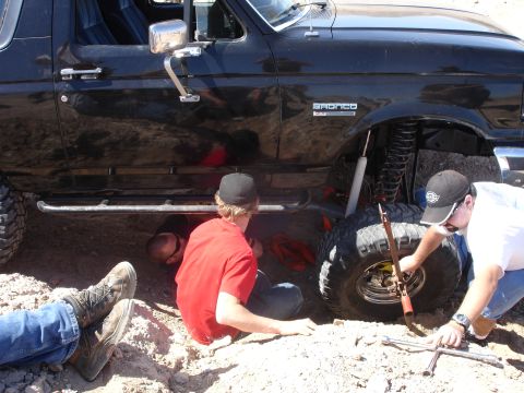 1996 Ford Bronco - People are working on the underside of a black Ford Bronco with a lifted suspension.