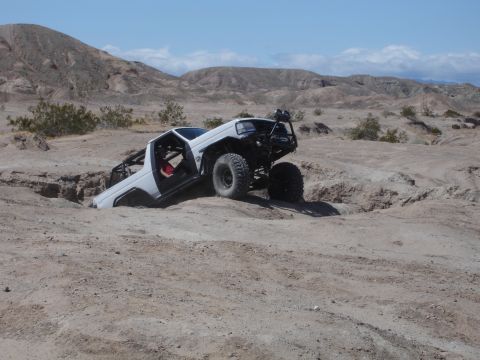 1996 Ford Bronco - White 1996 Ford Bronco stuck in a ditch during off-road excursion in a desert landscape.