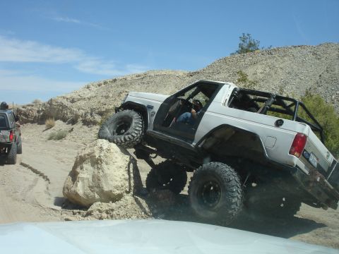 1996 Ford Bronco - Off-roading in the desert with a 1996 Ford Bronco tackling a large rock obstacle.