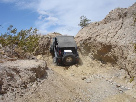 1996 Ford Bronco - Off-road vehicle navigates a steep, dusty incline in a desert landscape.