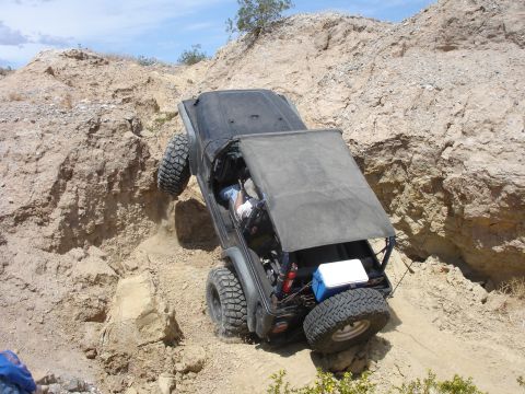 1996 Ford Bronco - Jeep Wrangler navigating a challenging off-road trail with steep, sandy terrain.