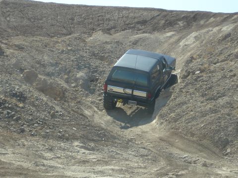 1996 Ford Bronco - Ford Bronco navigates a challenging off-road trail with steep, eroded terrain.