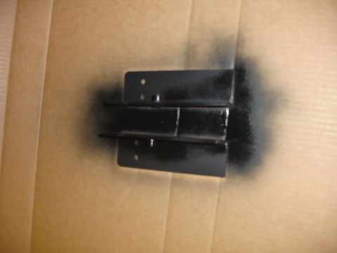 1996 Ford Bronco - A metal bracket is being spray painted black, likely for a vehicle part.