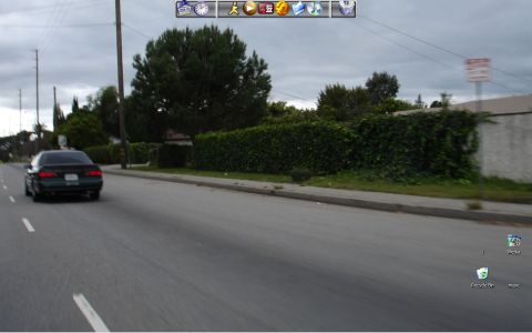1993 Ford Taurus - A dark sedan drives down a suburban street under a cloudy sky.
