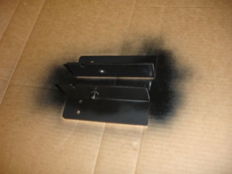 1996 Ford Bronco - Two black metal brackets are shown on a cardboard surface, likely after being painted.