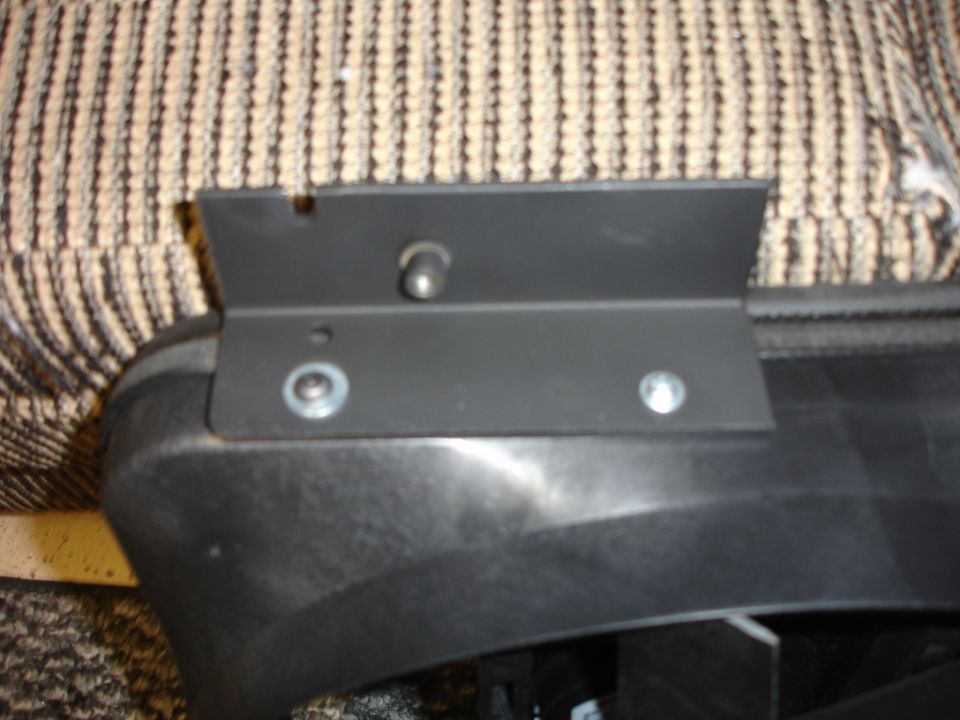 Black metal bracket with bolts attached to black plastic trim