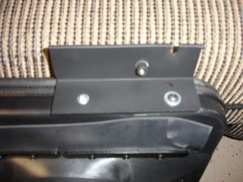 1996 Ford Bronco - Close-up of a black soft-top or tonneau assembly laid on beige carpet, showing the folded vinyl skin bolted to a black metal channel/rail w…