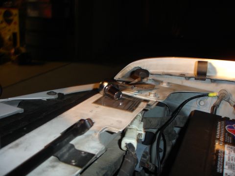 1996 Ford Bronco - Night shot under the raised hood of a white truck showing the core support and hood latch area, with a chrome ratchet resting on the latch…