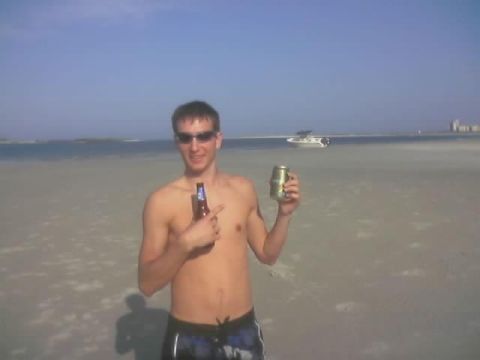 1989 Ford Bronco - A man enjoys drinks on a sunny day at the beach with a boat visible in the distance.