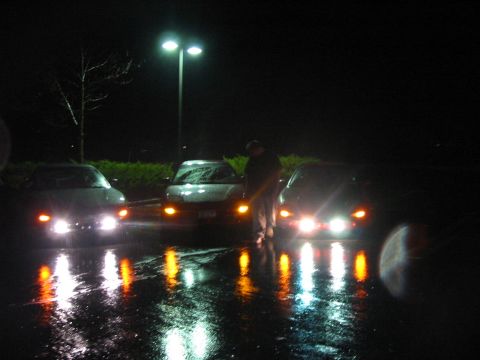1996 Ford Probe - Three cars are parked at night on a wet surface, their headlights illuminating the scene.