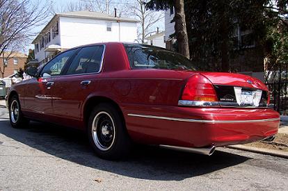 1999 Ford Crown Victoria - Rear 3/4 view of a red 1999 Ford Crown Victoria parked on a residential street.