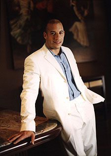 1987 Ford Bronco - Vin Diesel poses in a white suit, with a watermark for SuperMotors visible.