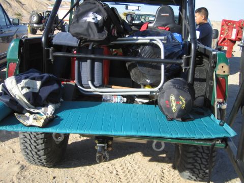 1985 Ford Bronco - The rear of a loaded off-road vehicle, with gear piled high and a person standing nearby.