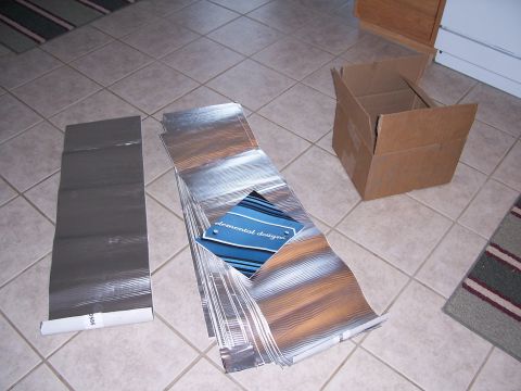 1978 Ford Bronco - Sheets of sound deadening material and an open cardboard box are laid out on a tiled floor.