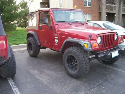 1998 Jeep TJ - A red Jeep Wrangler is parked next to another Jeep in a parking lot.