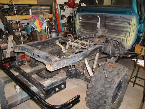 1989 Toyota Tacoma - This truck chassis is undergoing a project, with its bed removed and suspension components exposed. It is located in a workshop setting.