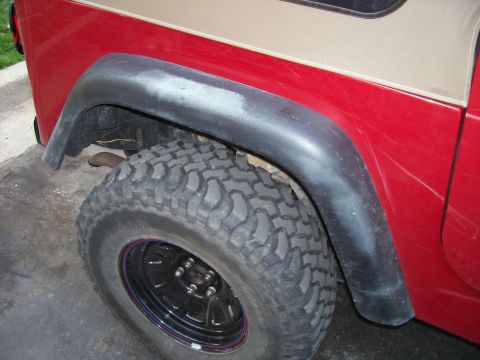 1998 Jeep TJ - Close-up of a Jeep Wrangler's rear fender and tire, showing body damage.