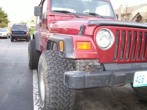 1998 Jeep TJ - Front corner of a red Jeep Wrangler, parked next to another SUV. The vehicle appears to be a 1997 model.