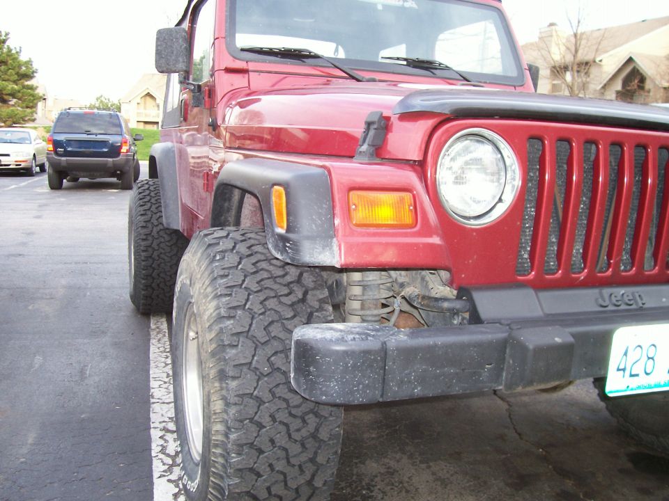 Red Jeep Wrangler 3q-front view, showing grille and large tires