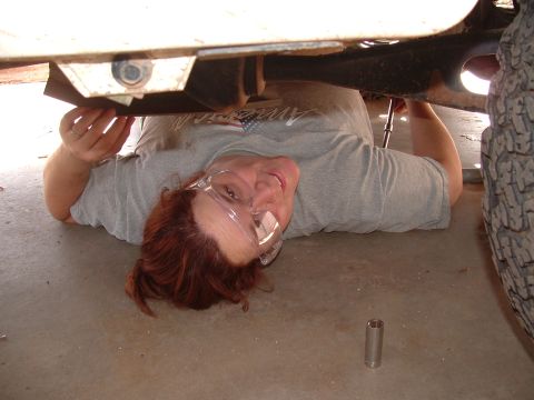 1990 Ford Bronco - A person lies on the ground, working on the underside of a vehicle, with a tire visible on the right.