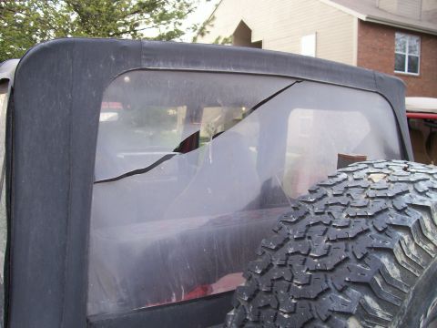 1998 Jeep TJ - Cracked rear soft top window on a Jeep Wrangler TJ, spare tire is in view.