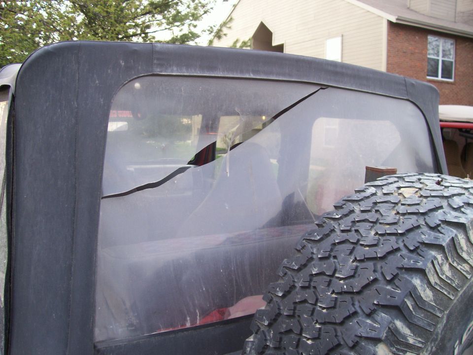 Jeep Wrangler TJ soft top rear window with a large crack; spare tire visible