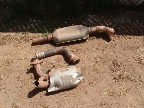 1990 Ford Bronco - Rusty exhaust system parts are visible on the ground, possibly from a vehicle.
