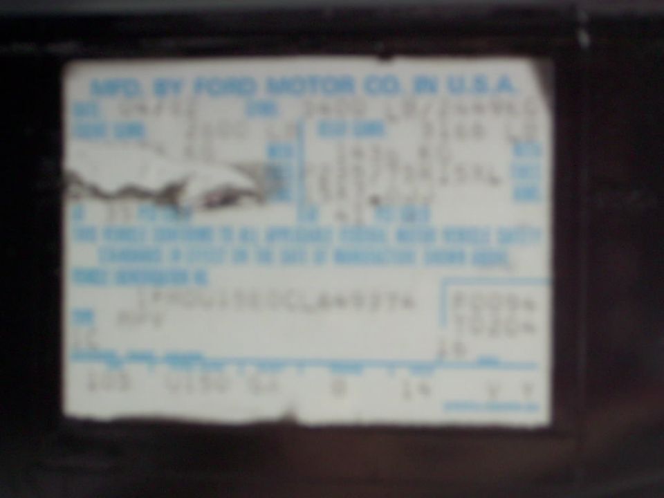 Blurry Ford Motor Co. vehicle certification label with mostly unreadable data