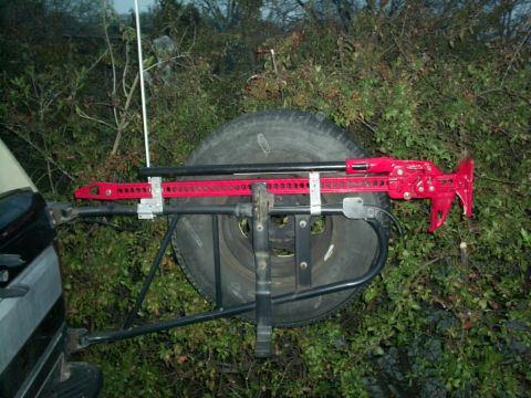 1994 Ford Bronco - Hi-lift jack mounted on a spare tire carrier, with a portion of the vehicle visible.