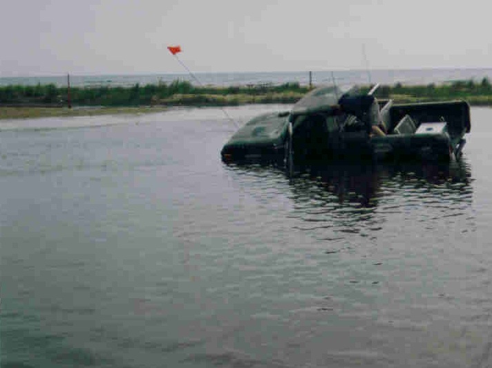 Truck partially submerged in water with an orange flag on a pole in the background