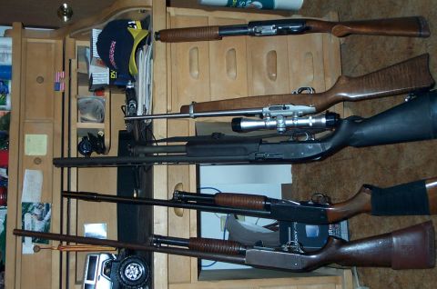 1984 Ford Bronco - A collection of firearms is displayed on a wooden rack, with a toy truck partially visible below.