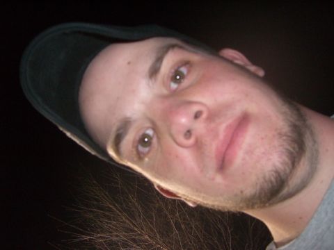 1985 Ford Bronco - A close-up photo of a man wearing a baseball cap, with a dark background and some vegetation.