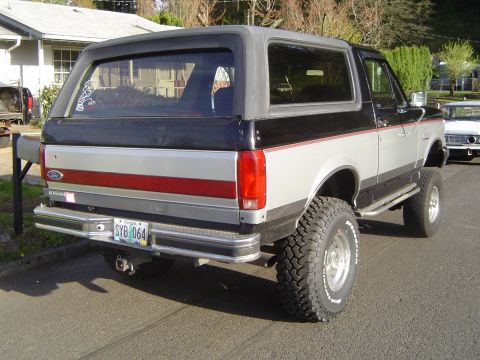 1989 Ford Bronco - Rear view of a lifted 1989 Ford Bronco showing its two-tone paint and aftermarket wheels.