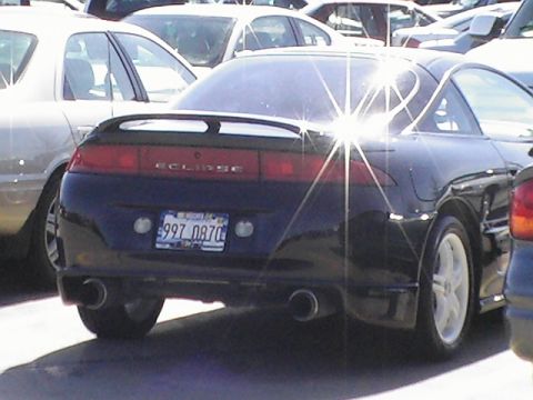 1994 Ford Probe - The rear of a black coupe, identified as an Eclipse, is visible with other vehicles parked around it.