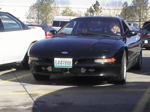 1994 Ford Probe - A black 1994 Ford Probe is parked in a lot next to another vehicle.