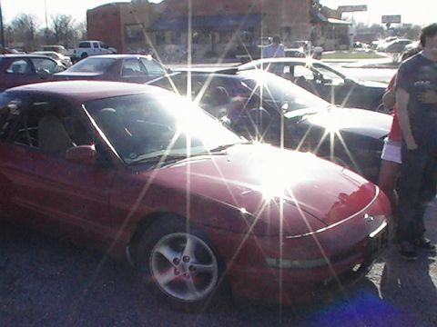 1994 Ford Probe - A red 1994 Ford Probe is parked in a lot with other vehicles and people nearby.