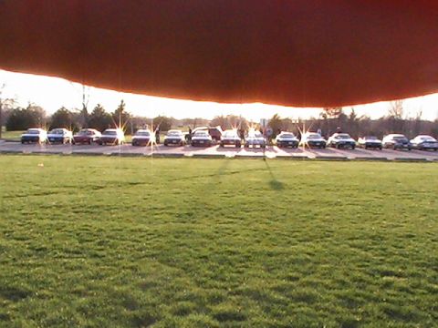 1994 Ford Probe - A line of vehicles is parked in a lot, with the sun setting behind them.