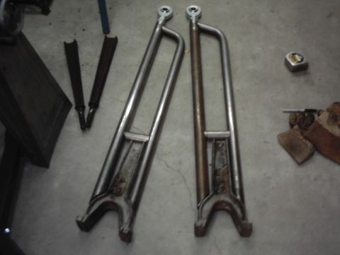 1978 Ford Bronco - A pair of fabricated tubular steel suspension radius arms lying on a concrete garage floor, each with a forked mounting end and a threaded…