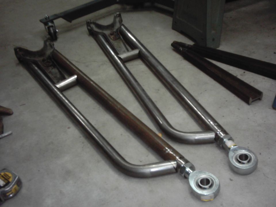 Pair of fabricated tubular radius arms with Heim joints on a shop floor